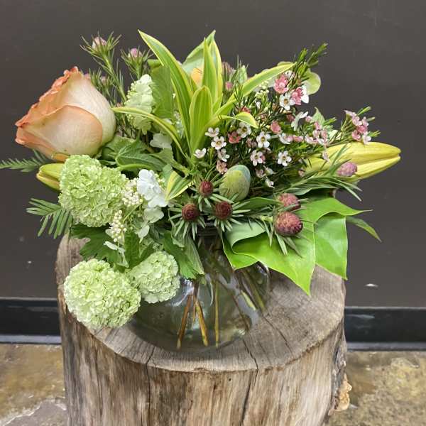Mixed bouquet in a glass vase with peach roses and green blooms