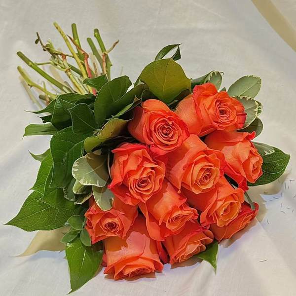 Bouquet of orange roses with green foliage on white wrapping