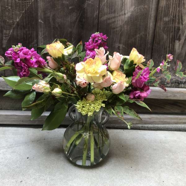 Bouquet of pink and yellow flowers in a clear glass vase