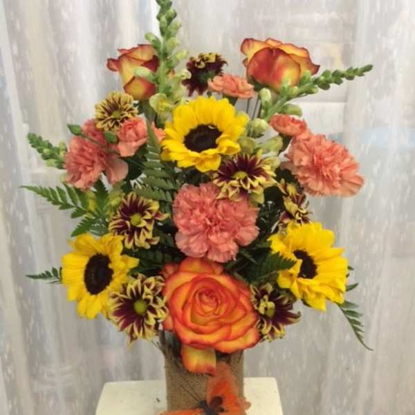 Bouquet of sunflowers, roses, and carnations in a glass vase