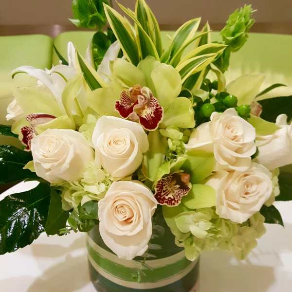 White roses and green orchids in a glass vase