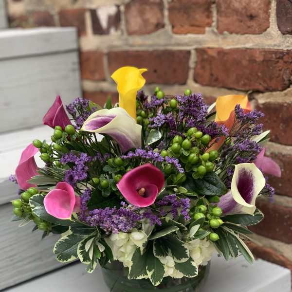 Mixed calla lily arrangement in a glass bowl vase