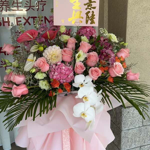 Large pink floral standing arrangement with roses and white orchids