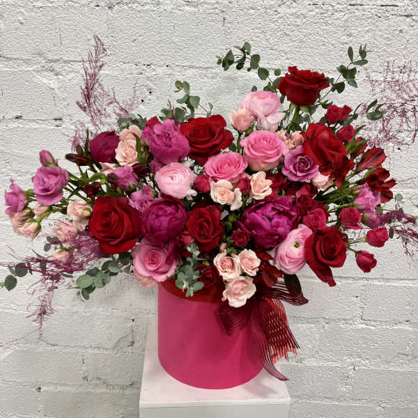 Large bouquet of red and pink roses in a pink hat box