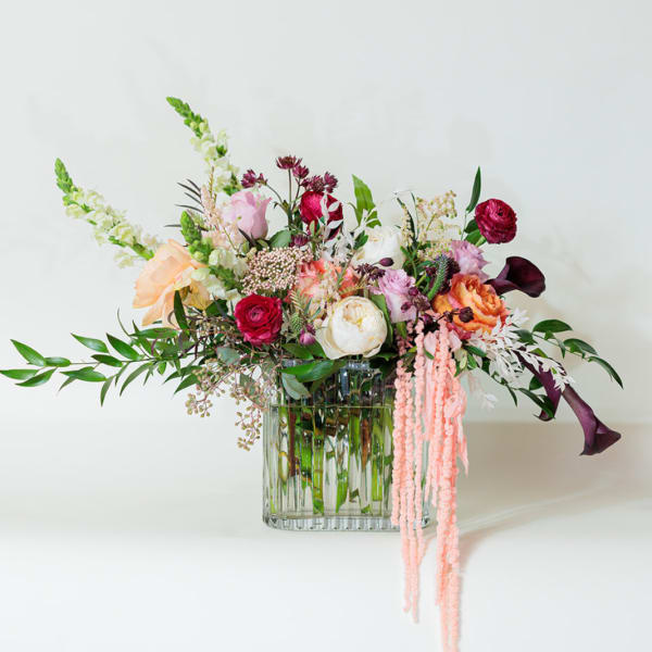 Mixed floral arrangement in a clear glass vase with pink, white, and burgundy blooms
