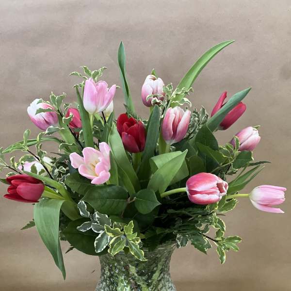 Pink and red tulips arranged in a textured glass vase