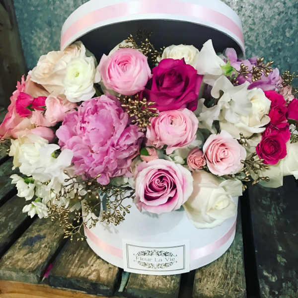 Pink and white roses arranged in a round hat box