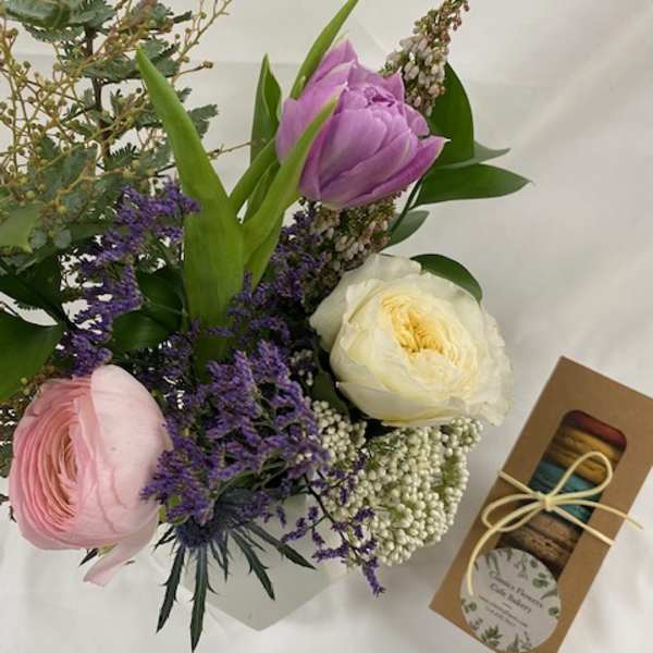 Bouquet of pink, purple, and white flowers with a box of macarons