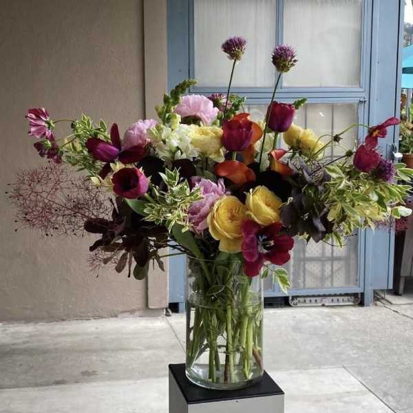 Mixed bouquet of tulips, roses, and calla lilies in a glass vase