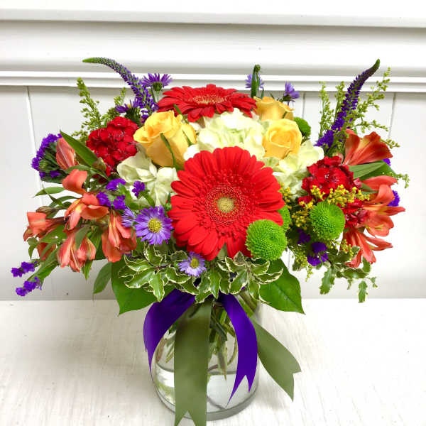 Bright mixed bouquet in a glass vase with red gerbera daisies and yellow roses