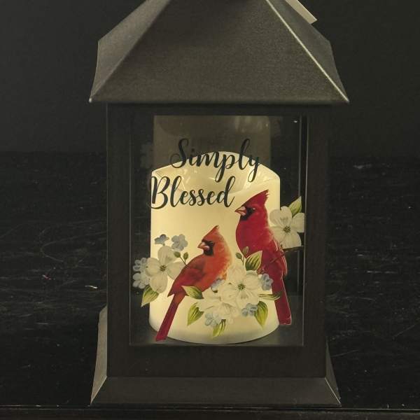 Black lantern with a candle labeled Simply Blessed and cardinals