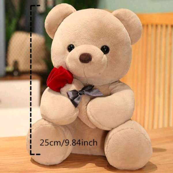 Beige teddy bear holding a red rose with a ribbon
