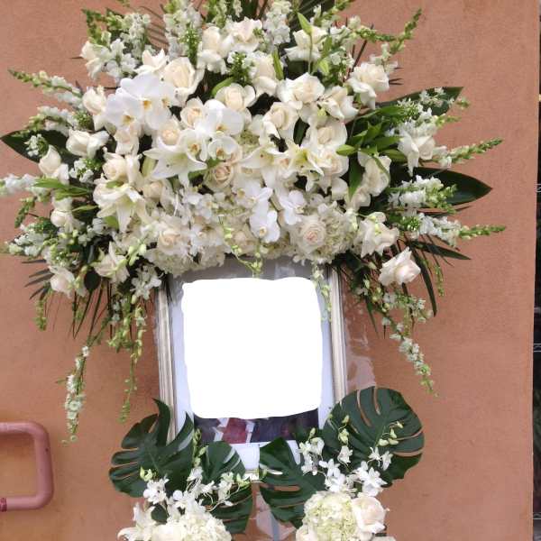 Large white funeral standing spray on an easel with orchids and roses