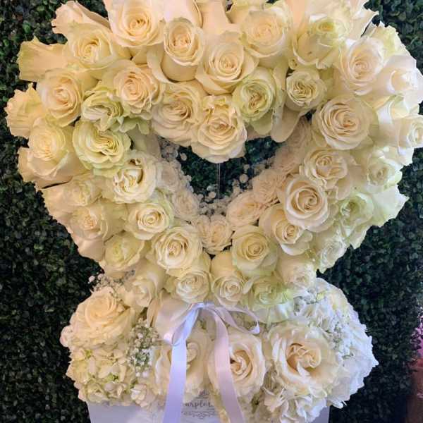 Heart-shaped arrangement of white roses with a ribbon bow
