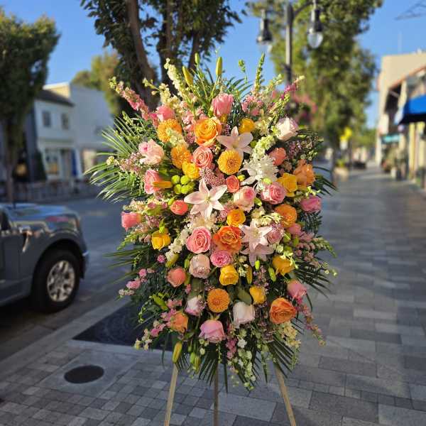 Large standing floral spray with pink, orange, and yellow blooms on an easel