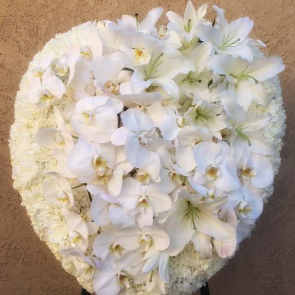 White orchid and lily funeral spray on a stand