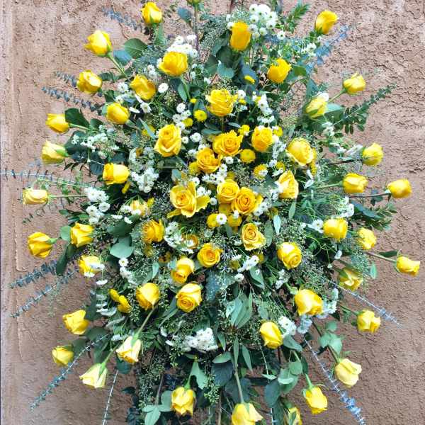 Large standing spray of yellow roses with white filler flowers