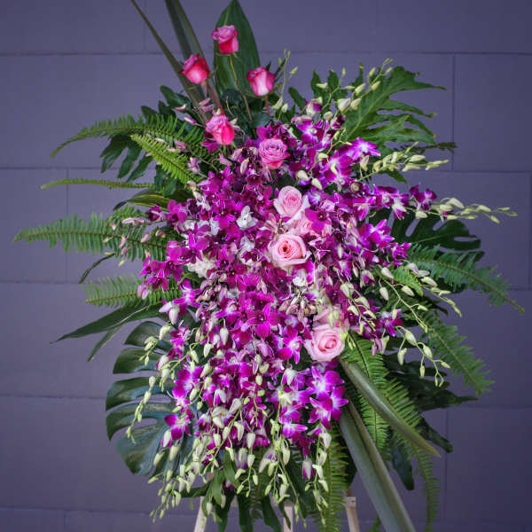 Tall floral spray with pink roses and purple orchids on an easel