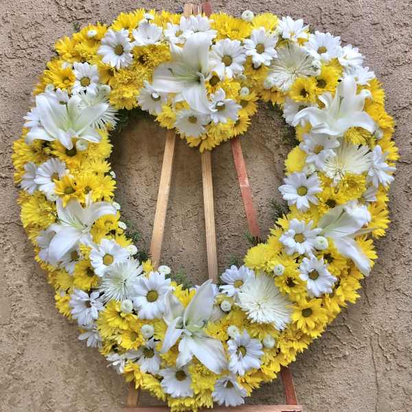 Heart-shaped floral wreath with white lilies and yellow and white daisies