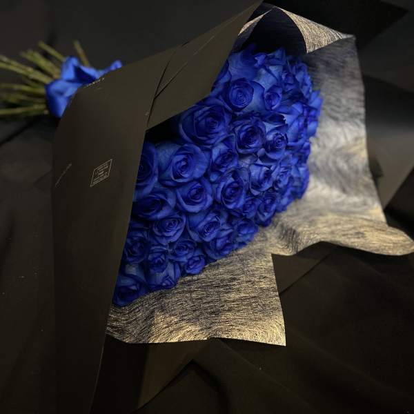 Bouquet of vivid blue roses wrapped in black paper