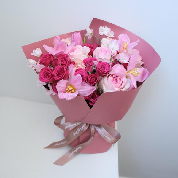 Pink bouquet of roses and tulips wrapped in pink paper