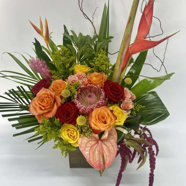 Tropical bouquet with roses, anthurium, and heliconia in a square vase