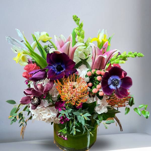 Colorful mixed flower arrangement in a green glass vase