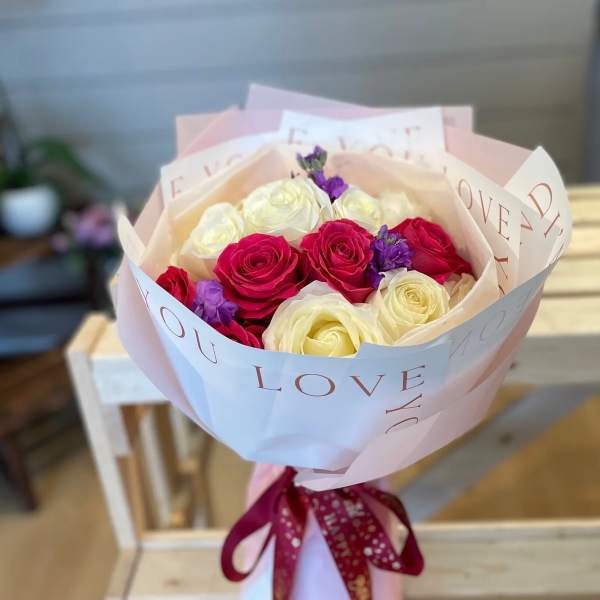 Bouquet of pink, white, and purple roses wrapped in paper