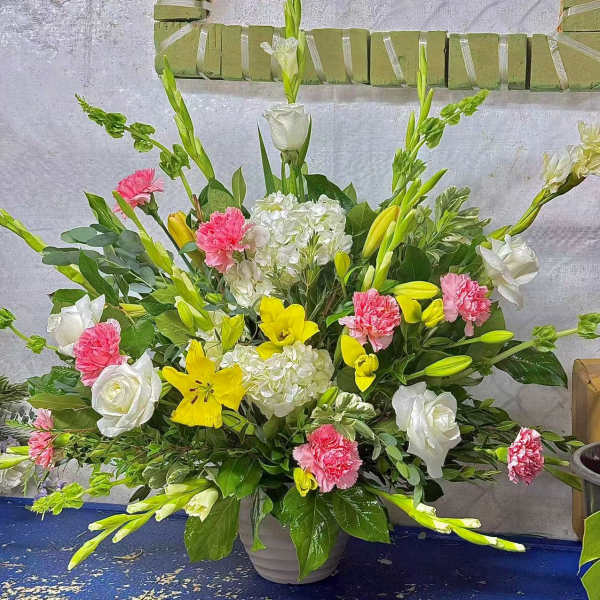 Large mixed floral arrangement in a gray vase with white, pink, and yellow blooms