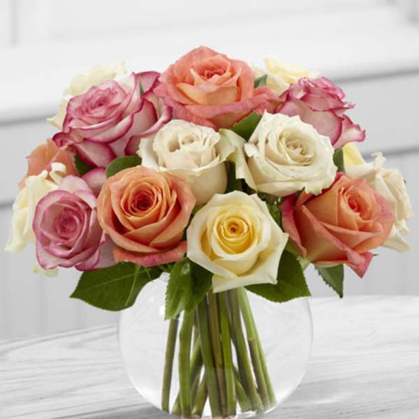 Bouquet of pink, peach, and white roses in a clear glass vase