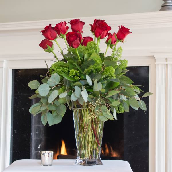 Tall vase arrangement of red roses with greenery
