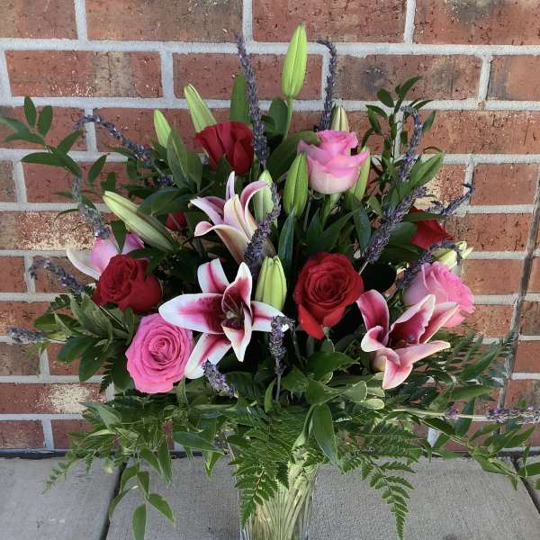 Mixed bouquet of pink and red roses with lilies in a glass vase