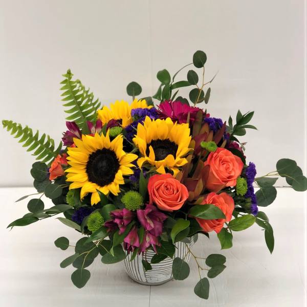 Bouquet of sunflowers and coral roses in a striped vase