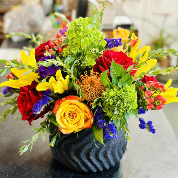 Colorful mixed flower arrangement in a dark textured vase