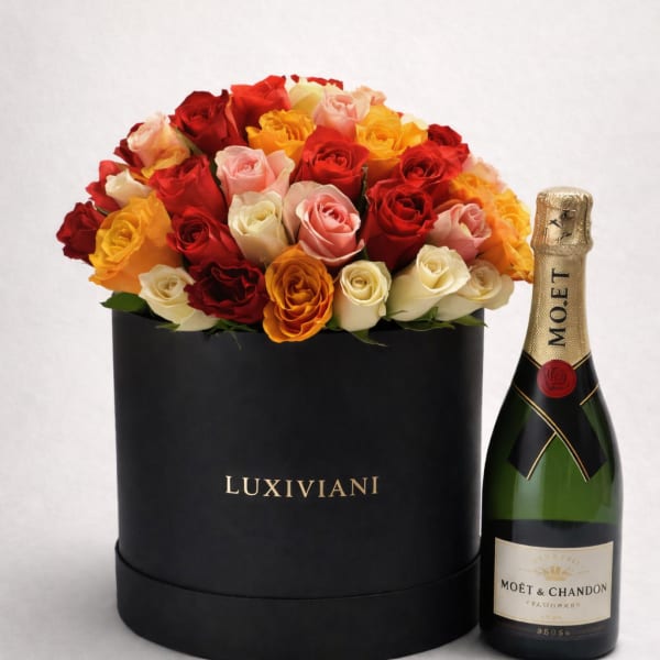 Box of multicolored roses beside a champagne bottle