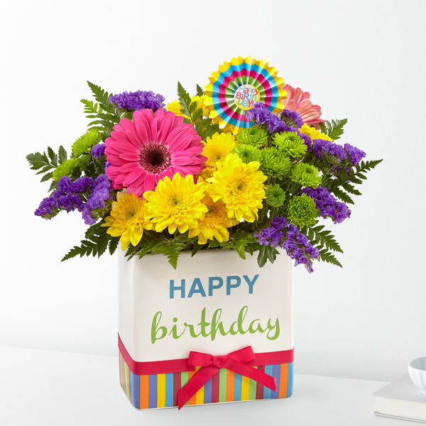 Birthday flower arrangement in a striped gift box with a ribbon