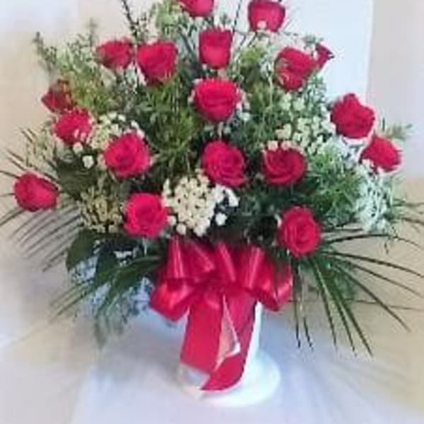 Bouquet of red roses with white filler flowers in a vase, tied with a red ribbon