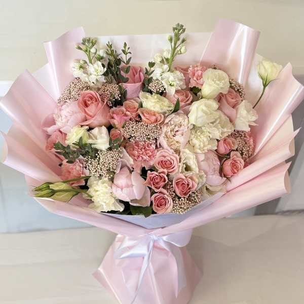 Bouquet of pink and white roses wrapped in pale pink paper