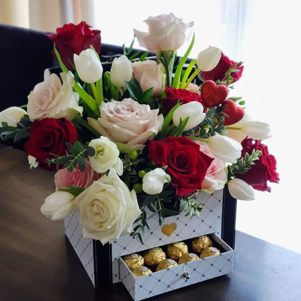 Bouquet of red and white roses with white tulips in a gift box with chocolates