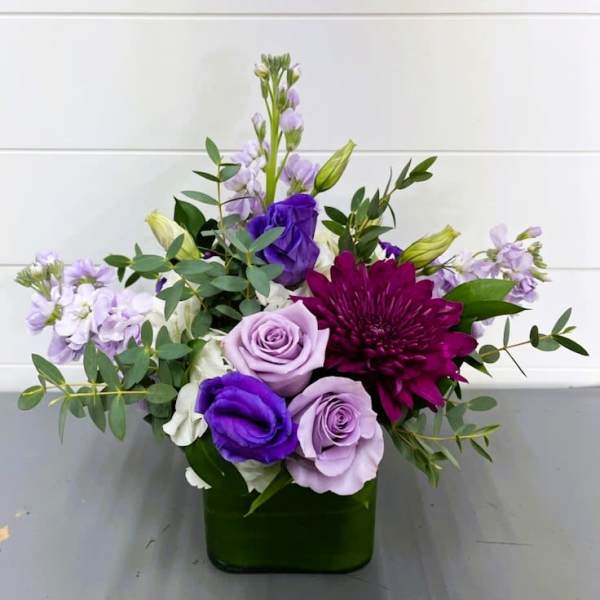 Purple and lavender flowers arranged in a green vase