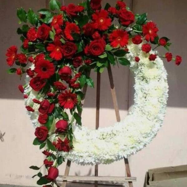 Heart-shaped floral wreath with red and white flowers on an easel