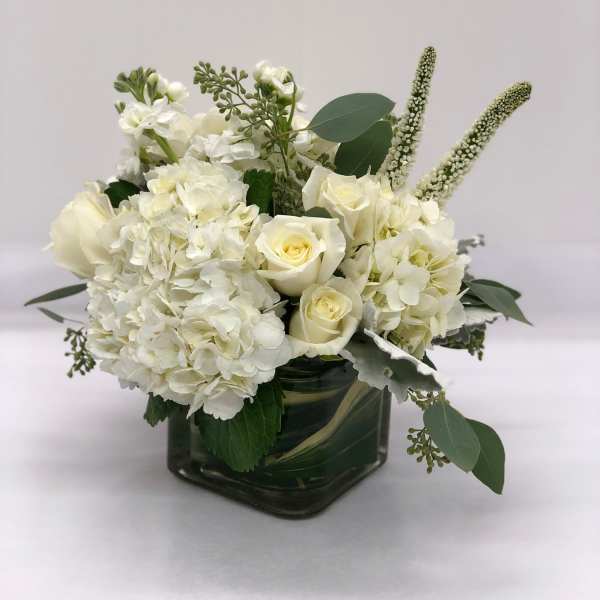 White roses and hydrangeas in a square glass vase