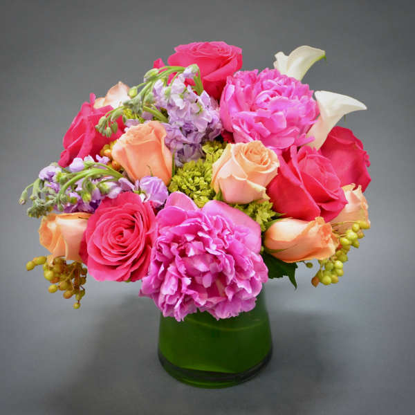 Pink and peach mixed bouquet in a green glass vase