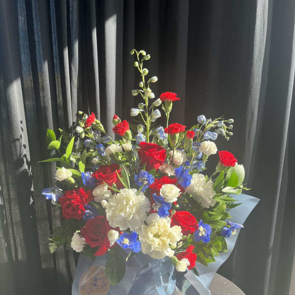 Bouquet of red, white, and blue flowers wrapped in pale blue paper