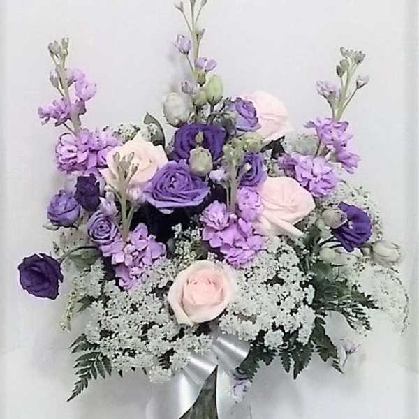 Lavender and pale pink bouquet in a glass vase with a silver ribbon