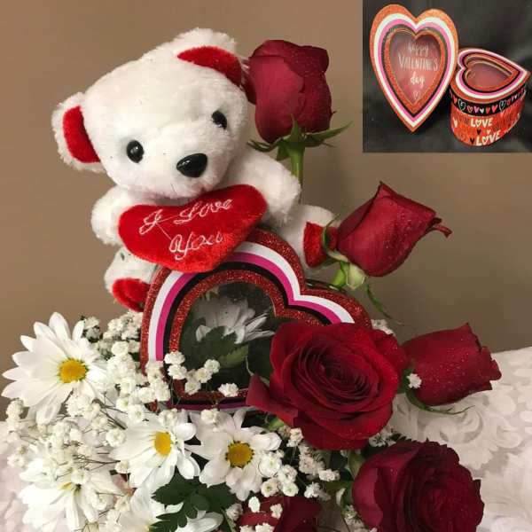 Teddy bear with red roses and white daisies in a Valentine gift arrangement