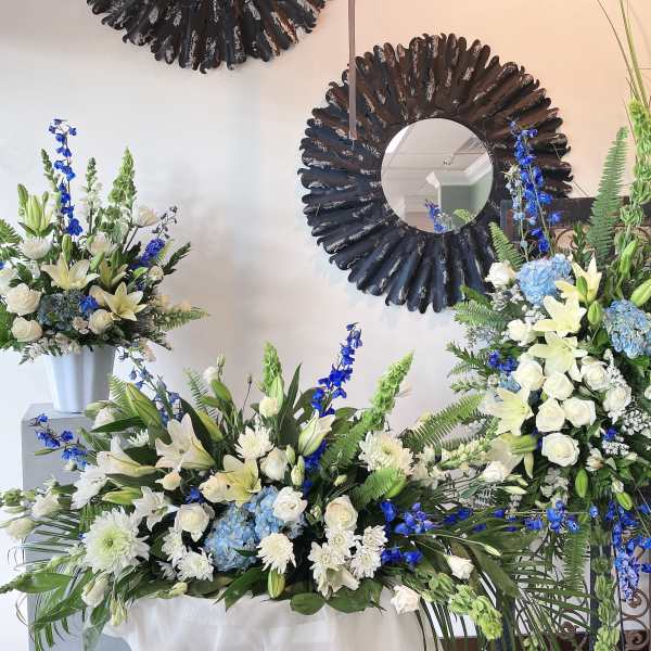 White and blue floral arrangements with lilies and roses in vases