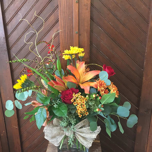Mixed bouquet in a glass vase with lilies, roses, and yellow daisies