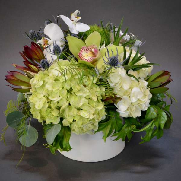 White and pale green floral arrangement in a white container