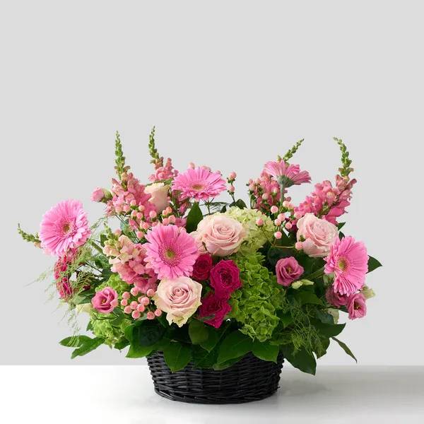 Pink mixed flower arrangement in a black basket
